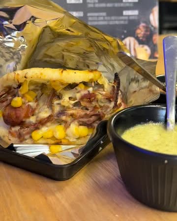 Arepa rellena con carne desmechada, maicitos y queso, con salsa de ajo al lado